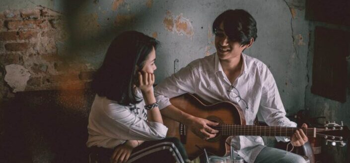 Man playing guitar while staring at the girl.
