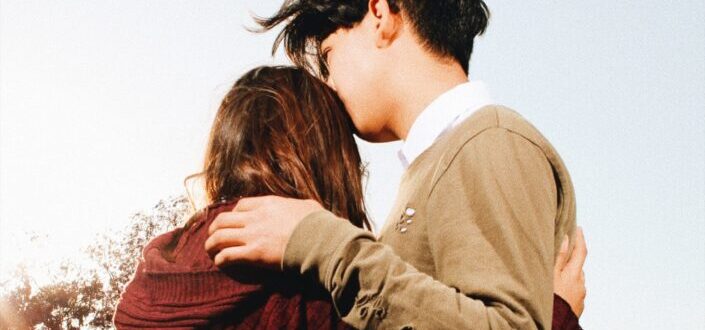 Young guy kissing her girlfriend on her forehead