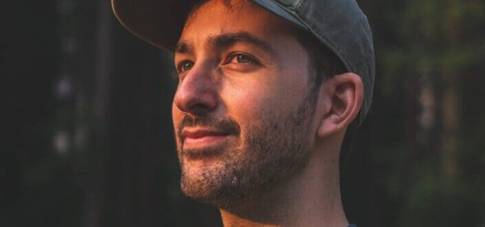 Young guy wearing cap timidly smiling