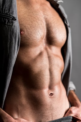 Muscular young man in grey shirt with trimmed short (Stubble Look) chest hair.