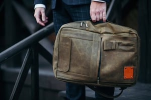 Man in a suit holding a stylish brown leather briefcase-style bag