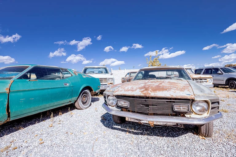 Rusty old cars in a scrapyard, showing the environmental impact of ageing vehicles.