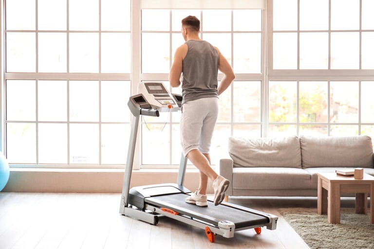 Man using a treadmill at home in a bright living room, illustrating choosing the right treadmill for home workouts