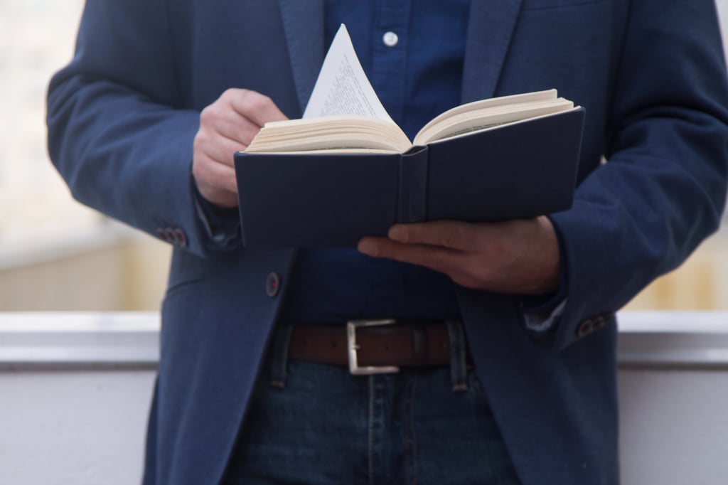 A man turning the page of one of the best books for men.