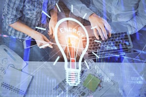 Business team analyzing data with a digital lightbulb graphic representing innovative energy solutions for lower commercial power costs