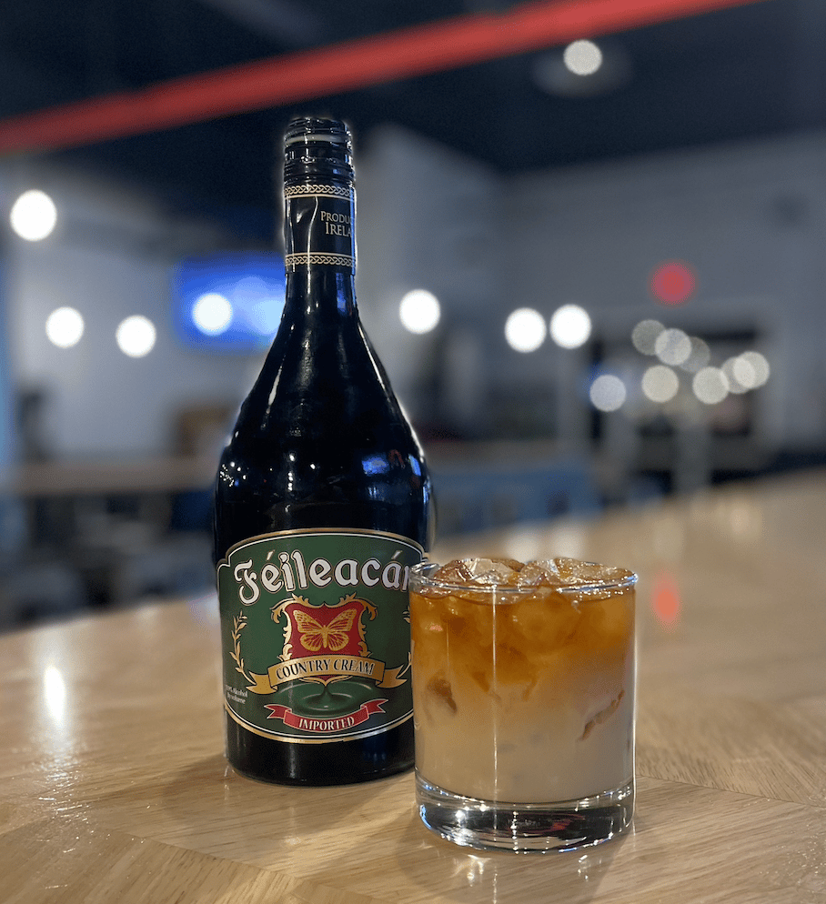 Bottle of Irish cream next to cup of iced coffee.