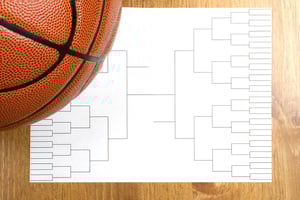 First-week March Madness basketball bracket with basketball sitting atop it.