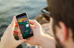 Person playing a mobile social casino game on a smartphone outdoors.