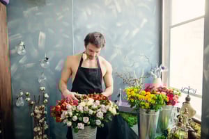 Person arranging silk flowers and wholesale décor elements to enhance an interior space with elegant event styling