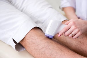Man receiving knee light therapy treatment with a handheld device, illustrating how LED therapy is applied for joint pain relief and recovery.