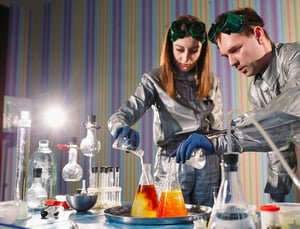 Two students conducting a chemistry experiment in a lab, mixing solutions with focus and precision to build understanding without burnout