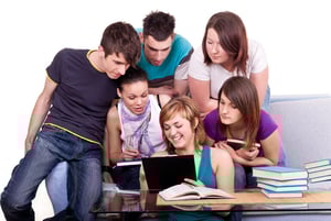 A group of students gathered around a laptop, engaged in online learning together, reflecting the collaborative and global nature of accredited international K–12 programs