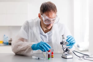 A biology professional wearing protective goggles and gloves carefully examining samples with a microscope in a laboratory