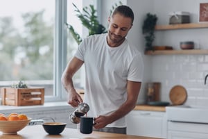 Man pouring coffee in a bright, modern kitchen with a relaxed morning routine