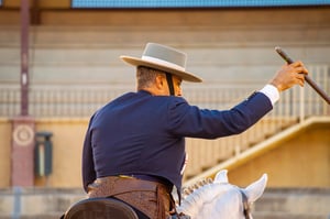 Man wearing a classic cowboy hat and tailored Western outfit while riding a horse, showcasing traditional style, craftsmanship, and confident outdoor presence
