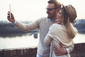 A man and a woman taking a selfie outdoors, capturing a relaxed and authentic moment that reflects modern dating through apps and real-life connections.