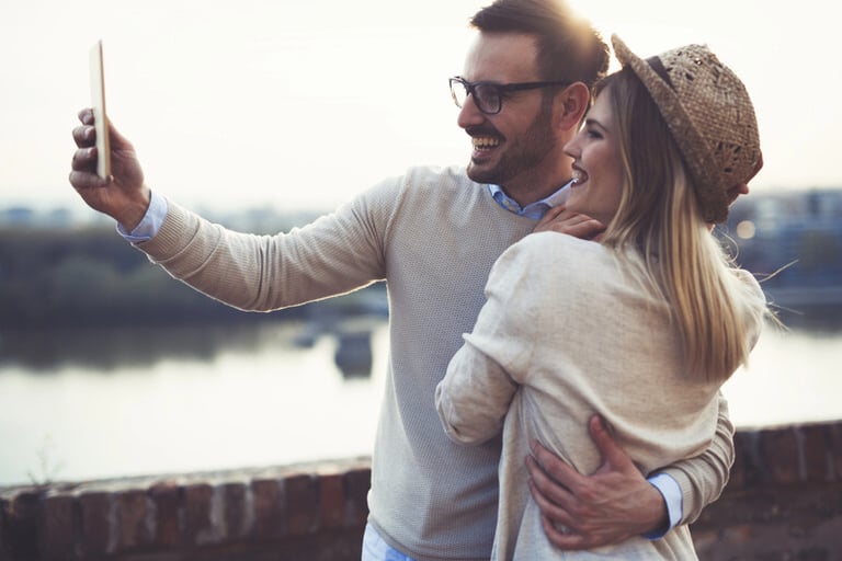 A man and a woman taking a selfie outdoors, capturing a relaxed and authentic moment that reflects modern dating through apps and real-life connections.