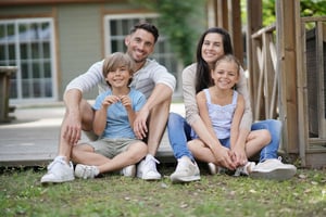 Happy family sitting together outside their home, representing support, stability, and a nurturing environment aligned with group home program values.