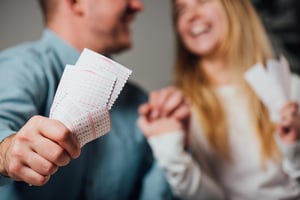 Couple holding lottery tickets and smiling together while enjoying lottery entertainment and anticipation of the draw.