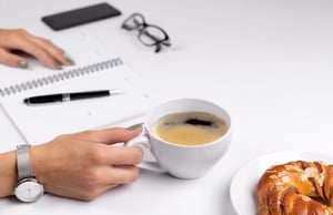 Breakfast setup with cup of espresso, notebook and a pen