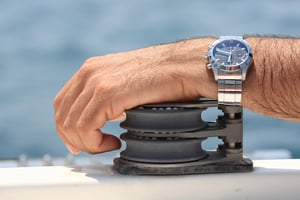 close-up of a dive watch on a man’s wrist near water