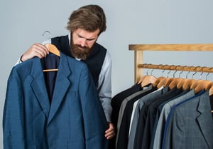 Man holding a blue coat and examining the fabric, reflecting the 2026 shift toward ethical clothing brands focused on quality, transparency, and long-term value