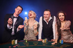 Group of players celebrating at a casino table with chips and cards during a lively gaming session.