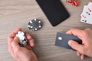 Hand holding casino chips and a card beside a smartphone, showing mobile payments in online gaming
