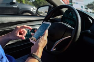 Driver using a mobile app inside a car to manage expenses and reduce costs after traffic violations.