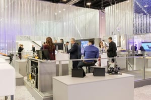 Visitors engage with a modern trade show booth featuring sleek displays, open design, and bright lighting.