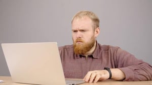 Man seated at a laptop, representing self-improvement challenges in an online environment.