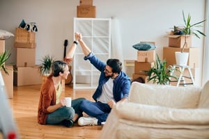 A couple is celebrating in their co-buying of a new house while sitting among moving boxes.
