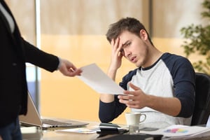 Man looking stressed while reviewing legal paperwork at his desk.