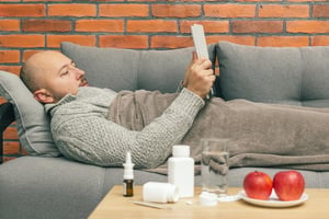 Man lying on a sofa using an iPad.