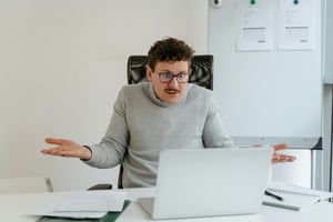 Man looking at laptop shrugging