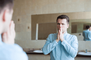 A man preparing in the mirror with social anxiety before a night out or a date.
